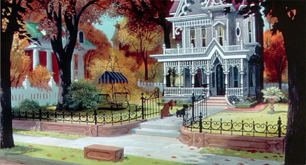 Les feuilles des arbres changent de couleur puisque c'est l'automne. Il y a deux chiens devant une grande maison blanche